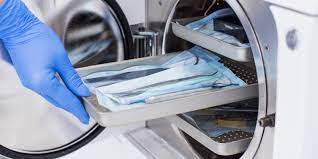 How LPG Has Changed Sterilization in The Medical Industry 3 An Image of a technician putting objects into a sterilizing machine, They are wearing a blue glove.